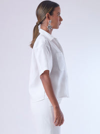 Blusa de corte recto y estilo relajado con manga corta amplia y cuello clásico. Está confeccionada en un tejido ligero y fresco, ideal para climas cálidos. Tiene dos bolsillos frontales de parche a la altura del pecho y una tapeta central que oculta los botones, lo que aporta un acabado limpio y pulido. Su diseño versátil combina elegancia casual y comodidad.