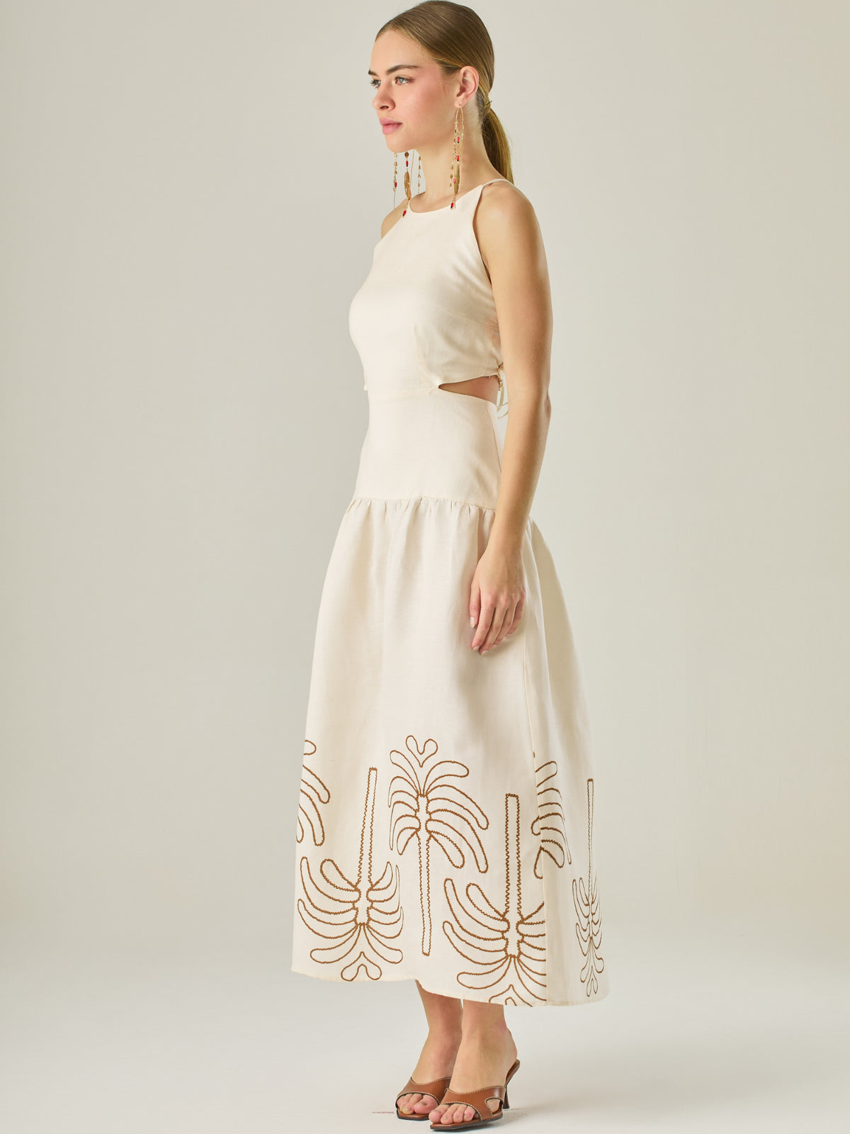 Vestido largo sin mangas con escote recto, aberturas laterales y detalle bordado en el bajo con motivos de inspiración natural. Su diseño limpio y femenino lo convierte en una opción ideal para un look sofisticado con un aire fresco y artesanal.
Detalles:
Color: Sand