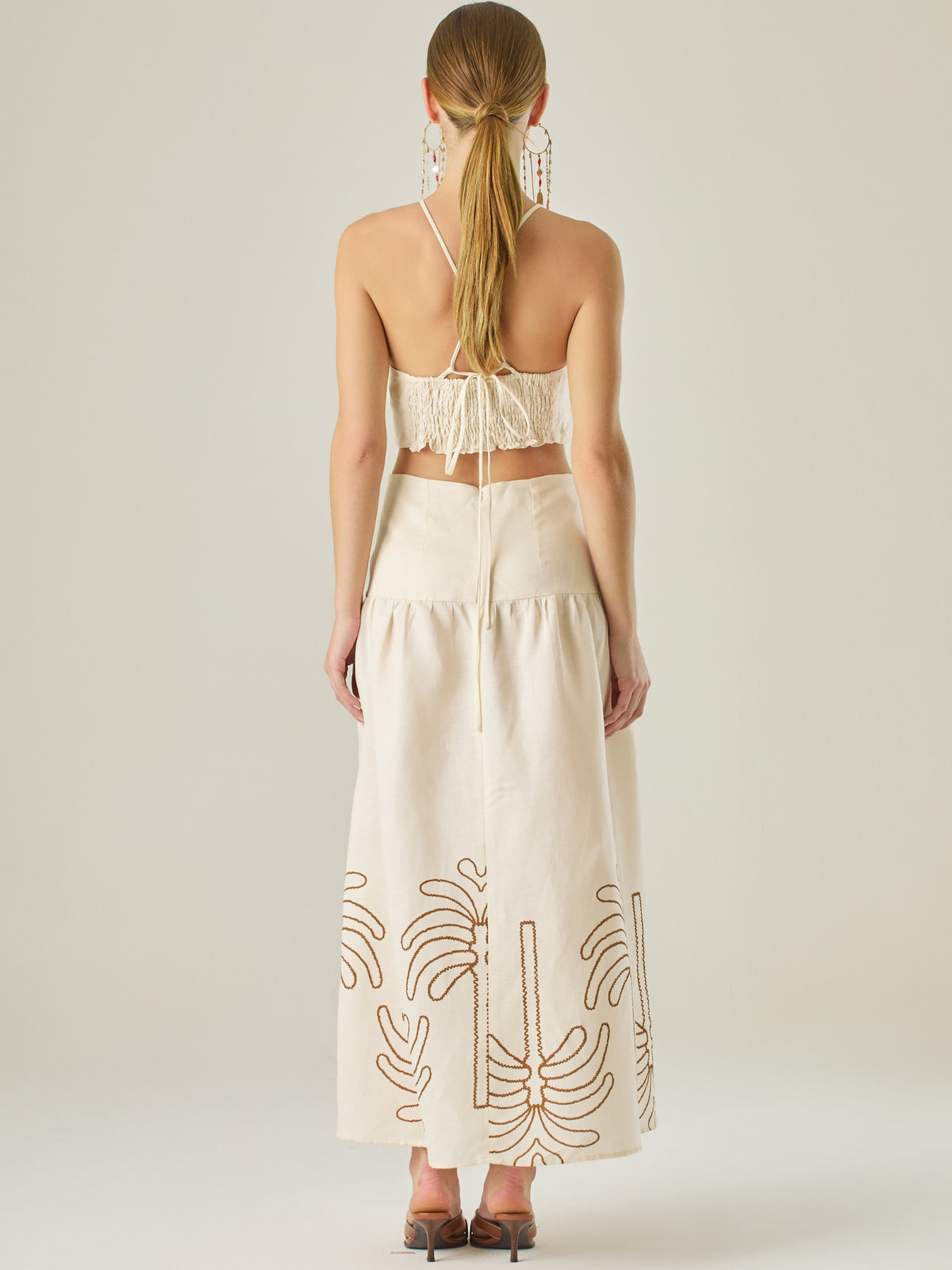 Vestido largo sin mangas con escote recto, aberturas laterales y detalle bordado en el bajo con motivos de inspiración natural. Su diseño limpio y femenino lo convierte en una opción ideal para un look sofisticado con un aire fresco y artesanal.
Detalles:
Color: Sand