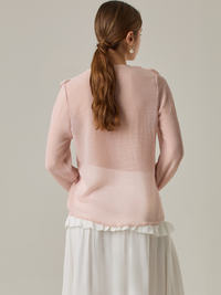 Blusa de manga larga confeccionada en un tejido ligero de textura sutil. Presenta un escote en "V" adornado con un amarre de tiras cruzadas, que añade un toque delicado al diseño. El frente está decorado con volantes que caen en capas suaves, aportando movimiento y un aire romántico. Las mangas tienen un ligero fruncido en los puños, creando un acabado abullonado discreto.

Detalles:

Color: Rosa