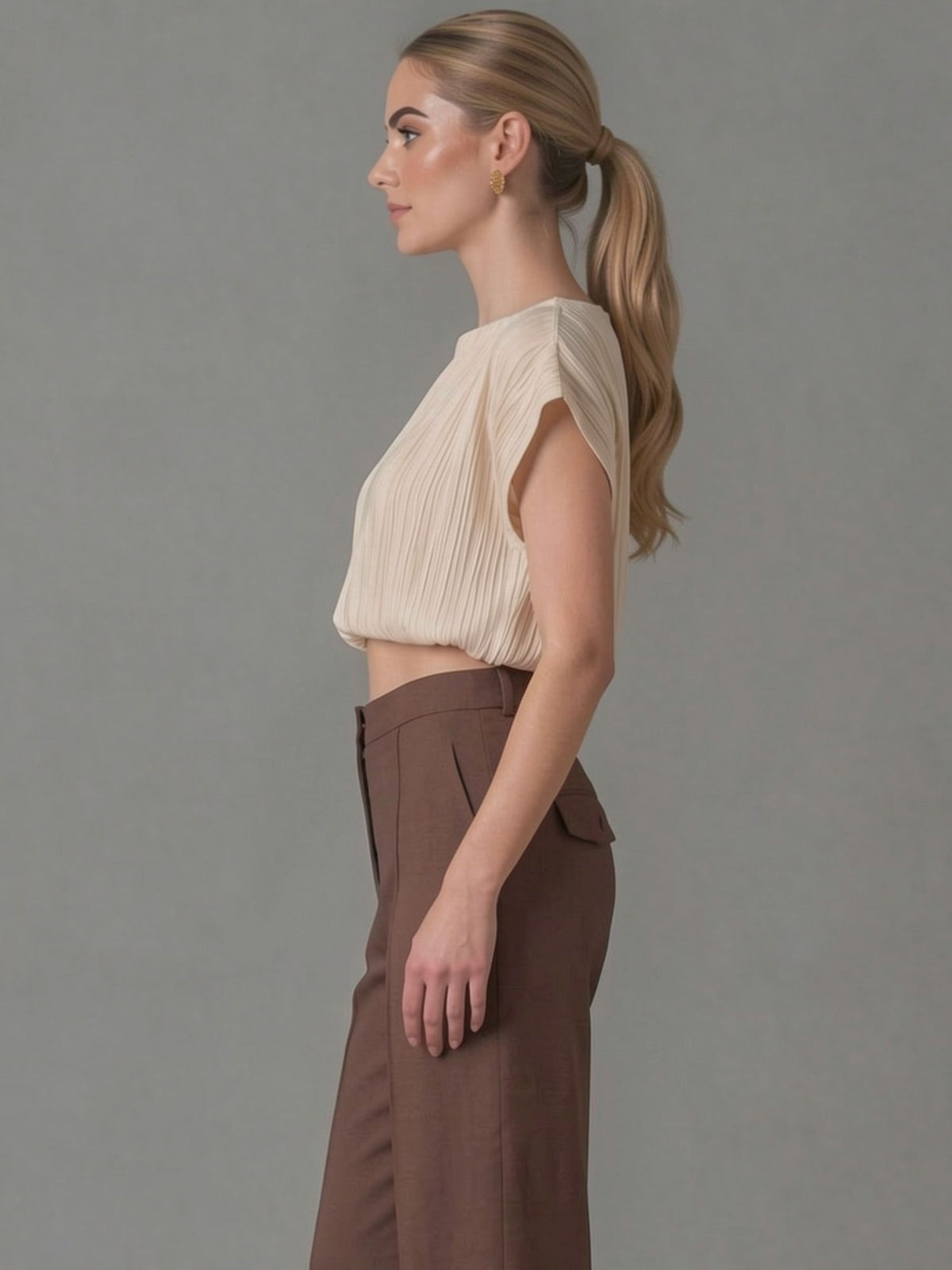 Top plisado beige de manga corta con un estilo moderno y minimalista. Su tejido ligero y su diseño elegante lo convierten en una prenda ideal para outfits de oficina o looks casual chic.