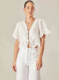 Blusa con guipiur, silueta corta y cierre con finos tirantes delantero, manga corta, estote pico, perfecta para días de playa o eventos especiales por su confección en lino 

Color: Blanco Perla 

Composición: 100% Lino 