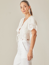 Blusa con guipiur, silueta corta y cierre con finos tirantes delantero, manga corta, estote pico, perfecta para días de playa o eventos especiales por su confección en lino 

Color: Blanco Perla 

Composición: 100% Lino 