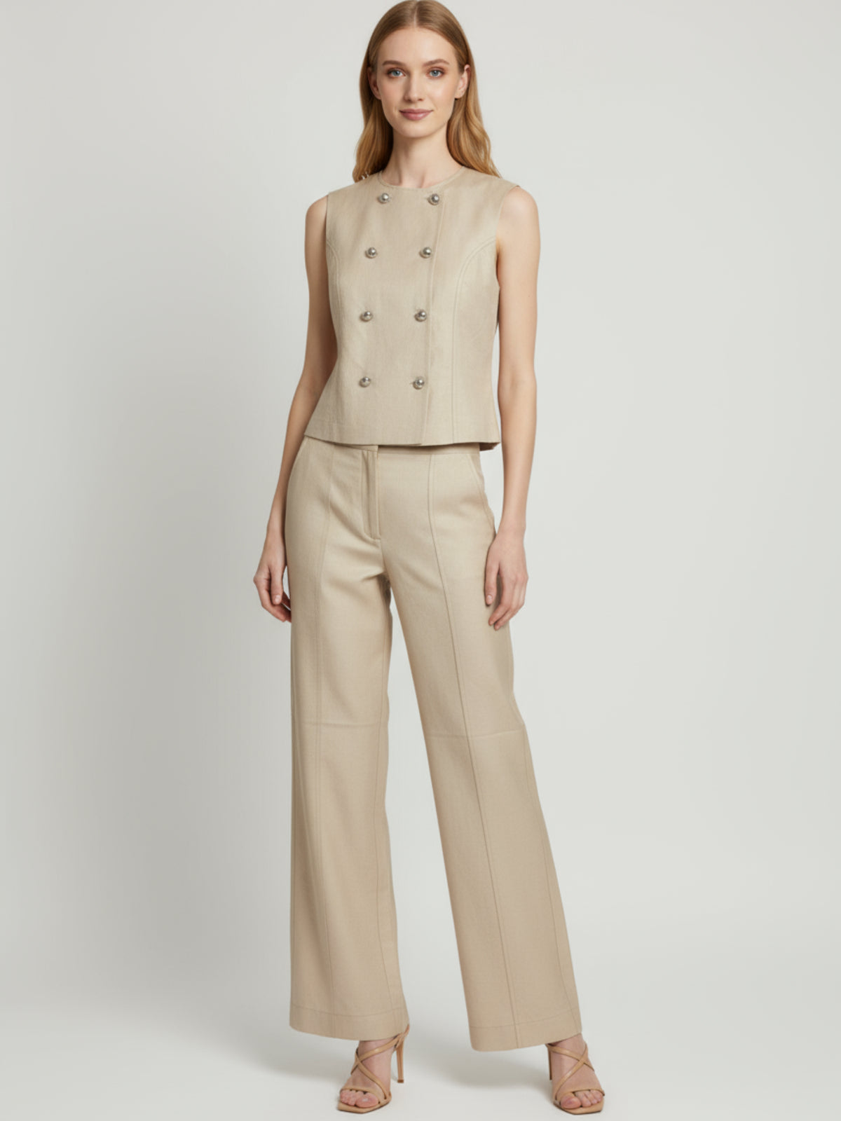 Blusa sin mangas  y cuello redondo, realzada por una doble hilera de botones tipo joya al frente. Las costuras verticales definen la figura y el largo a la cintura favorece tanto por dentro como por fuera