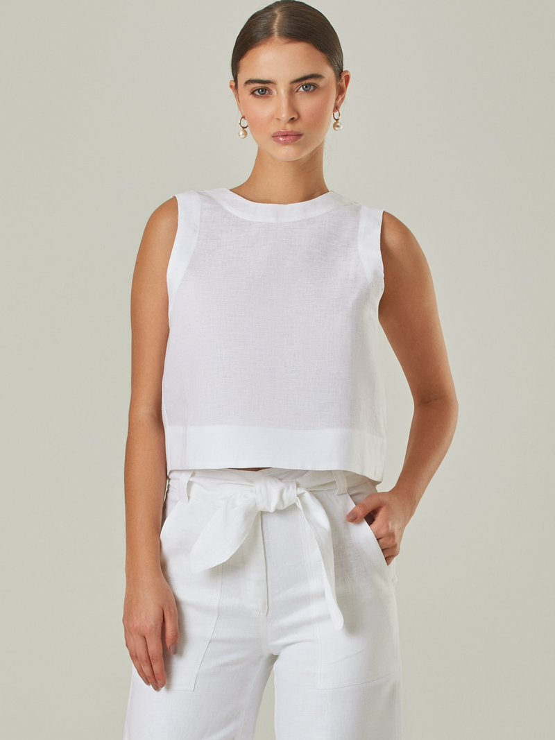Blusa de lino en color blanco, sin mangas y con un diseño minimalista y sofisticado. Su corte recto y acabado ligero la hacen perfecta para looks frescos y elegantes. Versátil y atemporal, ideal para combinar con pantalones de lino o faldas.