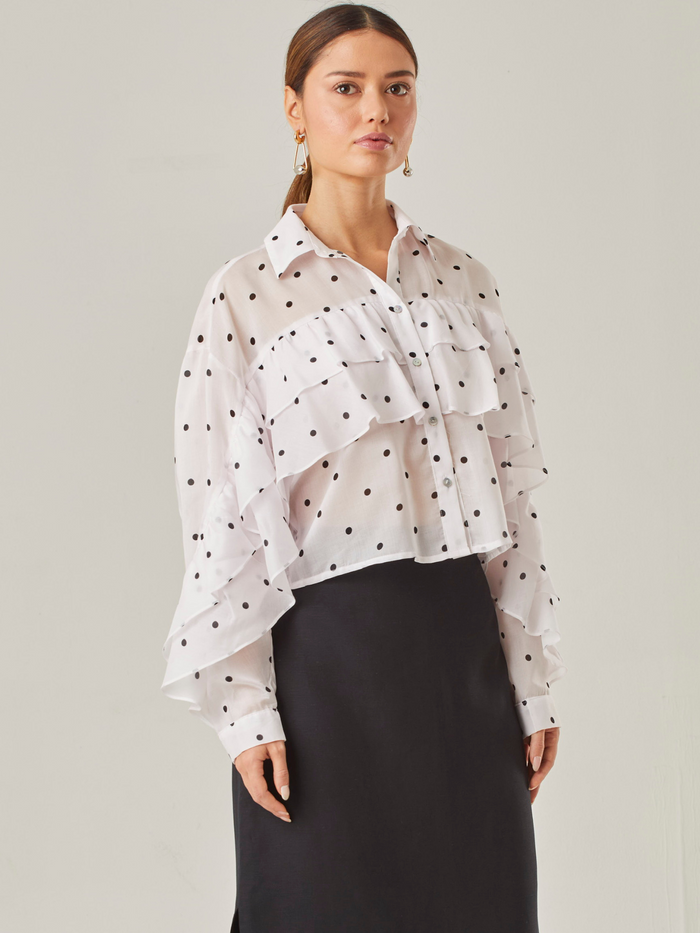 Esta blusa vaporosa de silueta relajada combina un estampado clásico de lunares con detalles delicados.