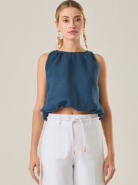 Blusa de estilo relajado destaca por su escote redondeado y un sutil efecto de fruncido en el cuello, que aporta un toque delicado. Su corte fluido y sin mangas la convierte en una prenda fresca y versátil, perfecta para looks casuales o para combinar con piezas más estructuradas. Ideal para días cálidos, añadiendo comodidad sin perder elegancia
