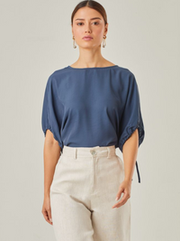 Blusa con un estilo relajado que combina comodidad y elegancia. Las mangas voluminosas, ajustables con delicados lazos, le otorgan un toque versátil, mientras que su corte fluido favorece una caída natural. Perfecta para crear looks modernos y atemporales.