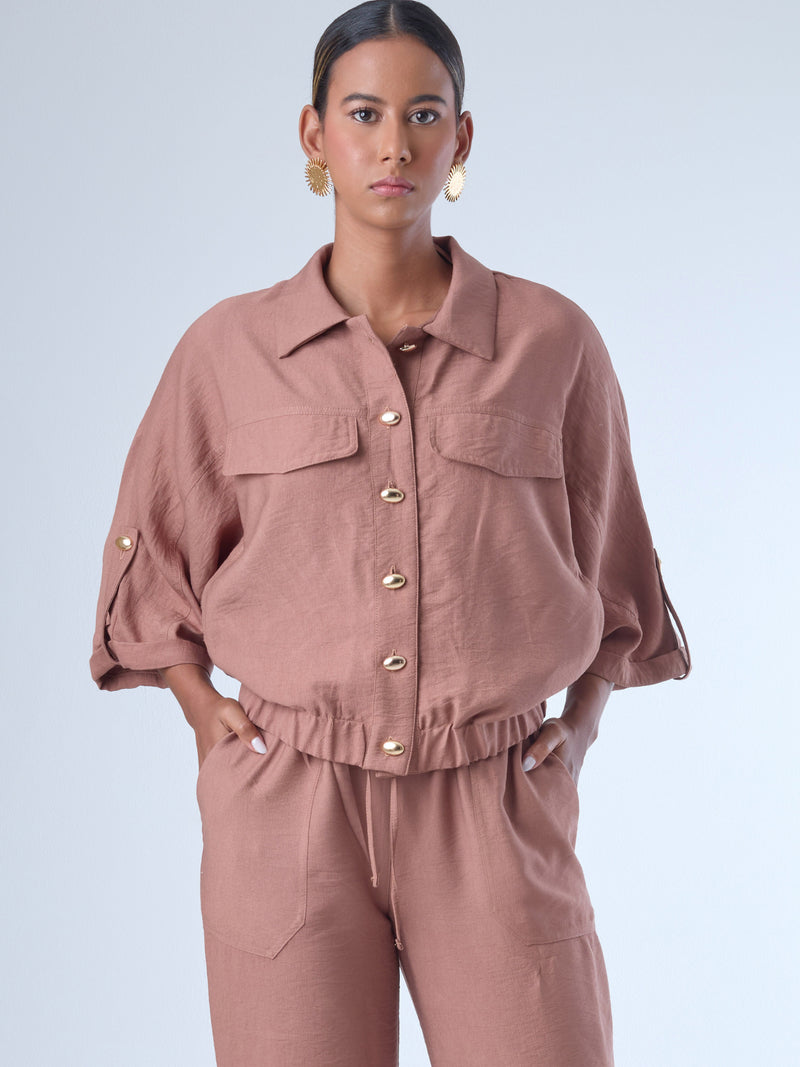 Relajada pero estructurada, esta blusa de silueta amplia combina un diseño utilitario con detalles refinados. Presenta bolsillos de solapa en el pecho, mangas con opción de ajuste y una botonadura dorada que aporta un toque de brillo sutil. Ideal para estilismos casuales con elegancia natural, o para elevar conjuntos relajados con una prenda clave y atemporal.