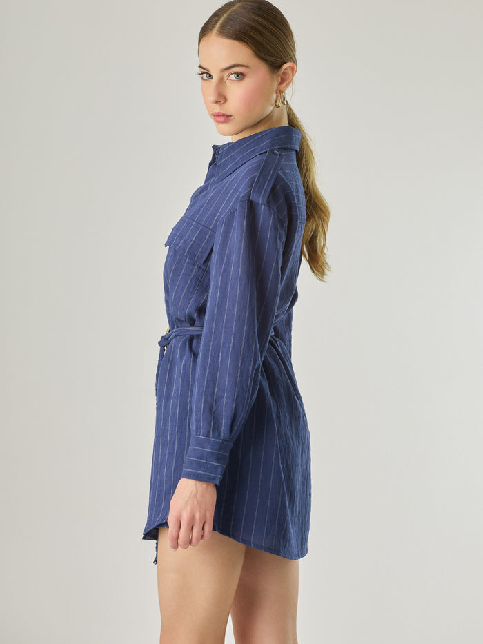 Blusa tipo camisera de manga larga con sutiles rayas y cinturón trenzado que define la figura. Su diseño ligero y relajado ofrece un estilo casual con toques elegantes, ideal para llevar con faldas o pantalones en looks versátiles y modernos.

Detalles:

Color: Navy

Material: 77% Rayon 23% Nylon

Características: Incluye cinturón a tono.