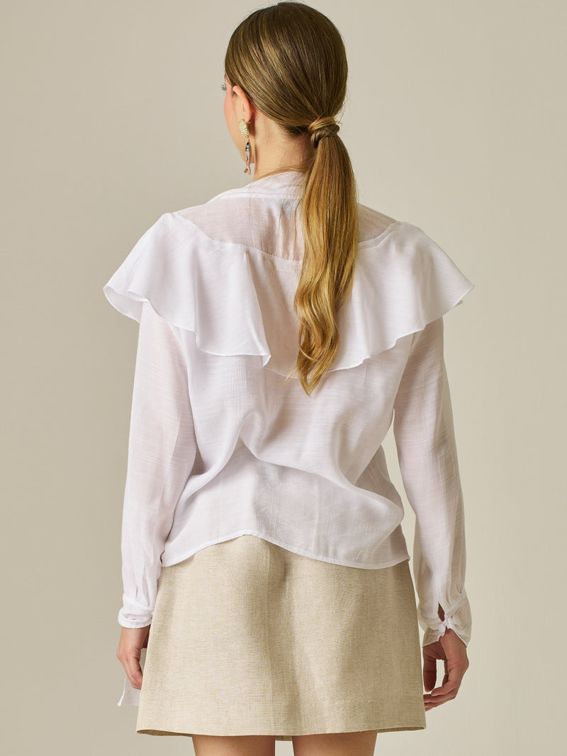 Blusa de manga larga con detalle de volantes en el escote y lazo largo para anudar. Su diseño ligero y delicado aporta movimiento y sofisticación, ideal para un look femenino con un aire romántico y moderno.

Detalles: