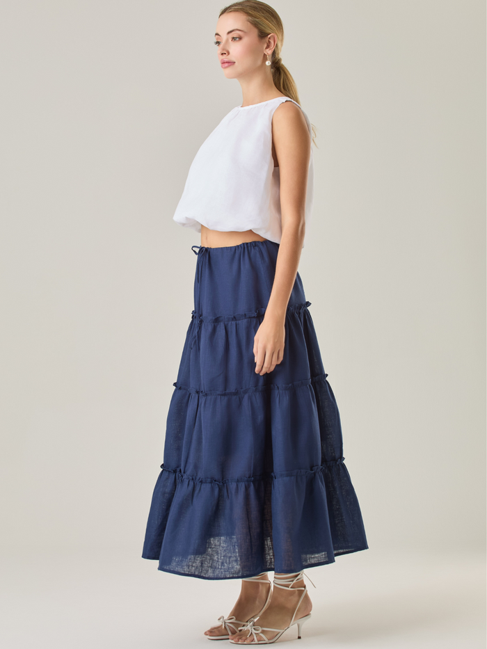 Esta falda larga de capas fruncidas aporta un aire fresco y fluido, ideal para un estilo relajado. Su pretina ajustable con cordón brinda comodidad y versatilidad, mientras que su caída ligera realza el movimiento natural de la prenda. Perfecta para combinar con blusas ligeras y looks casuales con un toque bohemio.