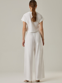 Pantalón de tiro alto y bota amplia que alarga visualmente la figura. Tiene una caída suelta y elegante que aporta movimiento con cada paso. Su diseño minimalista permite múltiples combinaciones, desde looks casuales hasta más sofisticados.

Detalles:

Color: Blanco Perla
