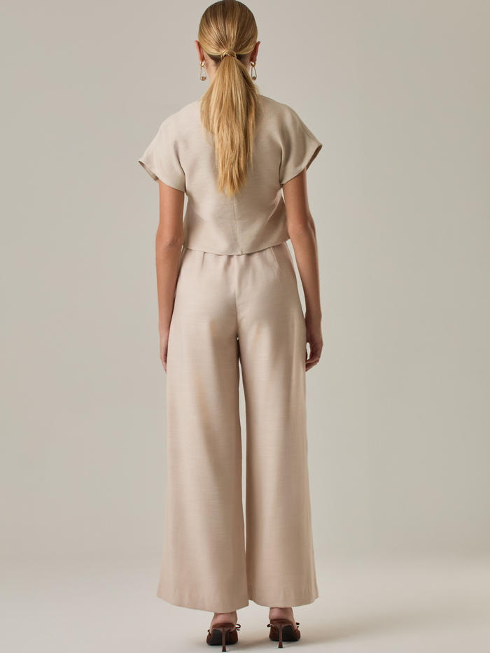 Pantalón de tiro alto y bota amplia que alarga visualmente la figura. Tiene una caída suelta y elegante que aporta movimiento con cada paso. Su diseño minimalista permite múltiples combinaciones, desde looks casuales hasta más sofisticados.

Detalles:

Color: Sand