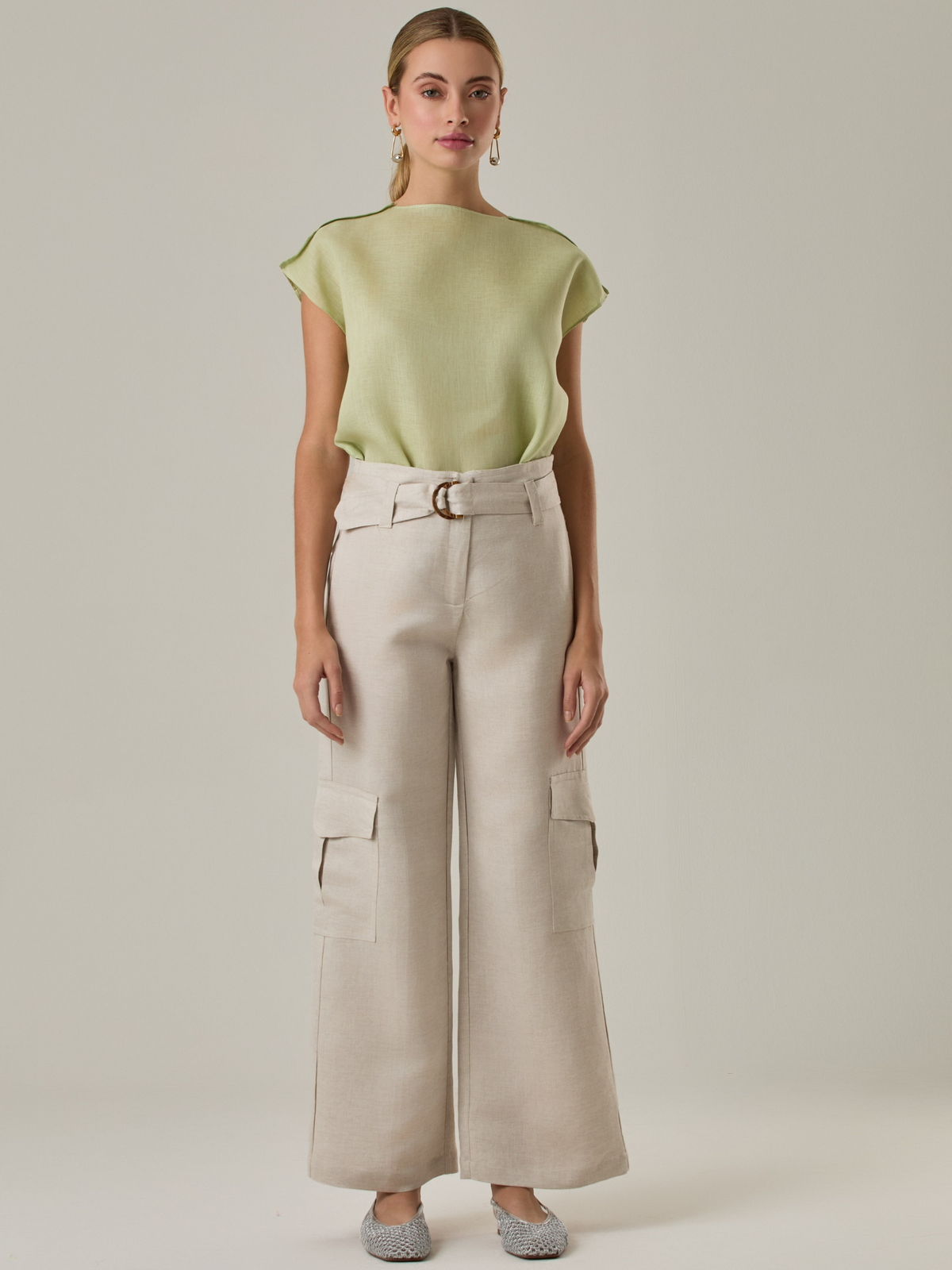 Pantalón amplio de tiro alto con bolsillos tipo cargo a los costados. Incluye cinturón del mismo tono con hebilla decorativa. Su silueta estructurada y el tono neutro lo convierten en una prenda versátil para looks casuales o sofisticados.

Color: Ivory

Material: 52% Lino 48% Rayón