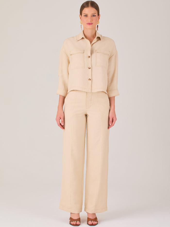 Este pantalón tiene un diseño sofisticado y moderno, confeccionado en un tono beige claro muy versátil. Presenta una silueta de pierna recta y ligeramente amplia, lo que aporta una caída elegante y cómoda. La cintura es de talle medio-alto, con cierre delantero oculto y detalles de pinzas que estilizan la figura. Incluye trabillas para cinturón y bolsillos laterales funcionales, además de costuras marcadas al frente que aportan estructura. Es una prenda ideal para looks de oficina, conjuntos monocromáticos 