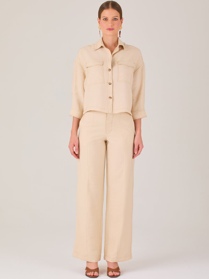 Este pantalón tiene un diseño sofisticado y moderno, confeccionado en un tono beige claro muy versátil. Presenta una silueta de pierna recta y ligeramente amplia, lo que aporta una caída elegante y cómoda. La cintura es de talle medio-alto, con cierre delantero oculto y detalles de pinzas que estilizan la figura. Incluye trabillas para cinturón y bolsillos laterales funcionales, además de costuras marcadas al frente que aportan estructura. Es una prenda ideal para looks de oficina, conjuntos monocromáticos 