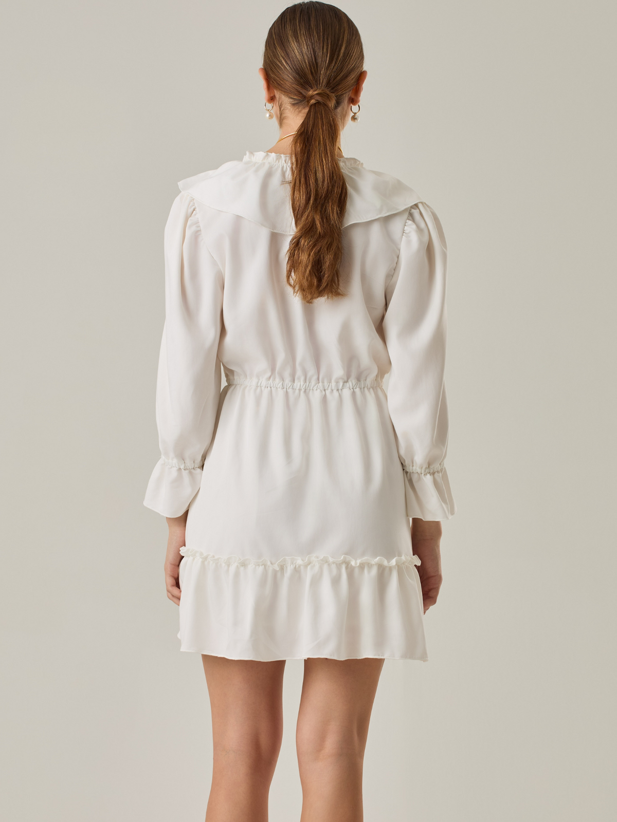 Vestido corto con volantes en el escote en V y en el ruedo. Tiene mangas largas con puños fruncidos y ajuste en la cintura con cordón. Su estilo femenino y romántico lo hace ideal para ocasiones casuales con un toque delicado.

Detalles:

Color: Blanco Perla 