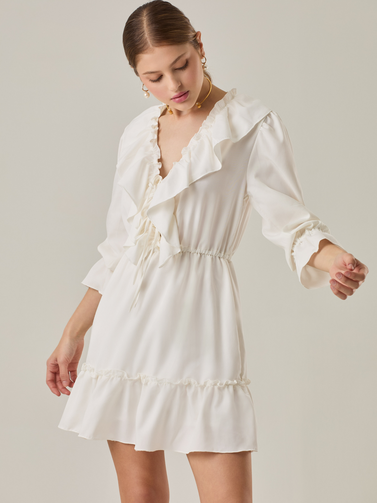 Vestido corto con volantes en el escote en V y en el ruedo. Tiene mangas largas con puños fruncidos y ajuste en la cintura con cordón. Su estilo femenino y romántico lo hace ideal para ocasiones casuales con un toque delicado.

Detalles:

Color: Blanco Perla 