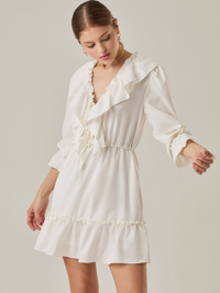 Vestido corto con volantes en el escote en V y en el ruedo. Tiene mangas largas con puños fruncidos y ajuste en la cintura con cordón. Su estilo femenino y romántico lo hace ideal para ocasiones casuales con un toque delicado.

Detalles:

Color: Blanco Perla 