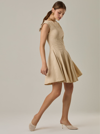 Vestido corto con silueta entallada en la parte superior y falda amplia. Tiene cuello cerrado tipo caja, mangas pequeñas que apenas cubren los hombros y costuras que definen la estructura del torso. La falda incorpora pliegues profundos que le dan volumen y movimiento. El largo llega por encima de la rodilla. Cierre invisible en la espalda.

Detalles:

Color: Ivory