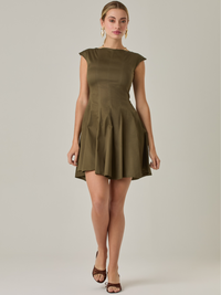 Vestido corto con silueta entallada en la parte superior y falda amplia. Tiene cuello cerrado tipo caja, mangas pequeñas que apenas cubren los hombros y costuras que definen la estructura del torso.