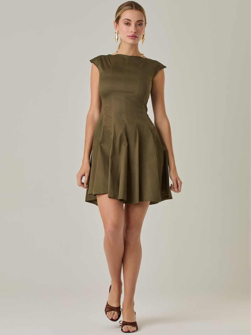 Vestido corto con silueta entallada en la parte superior y falda amplia. Tiene cuello cerrado tipo caja, mangas pequeñas que apenas cubren los hombros y costuras que definen la estructura del torso.