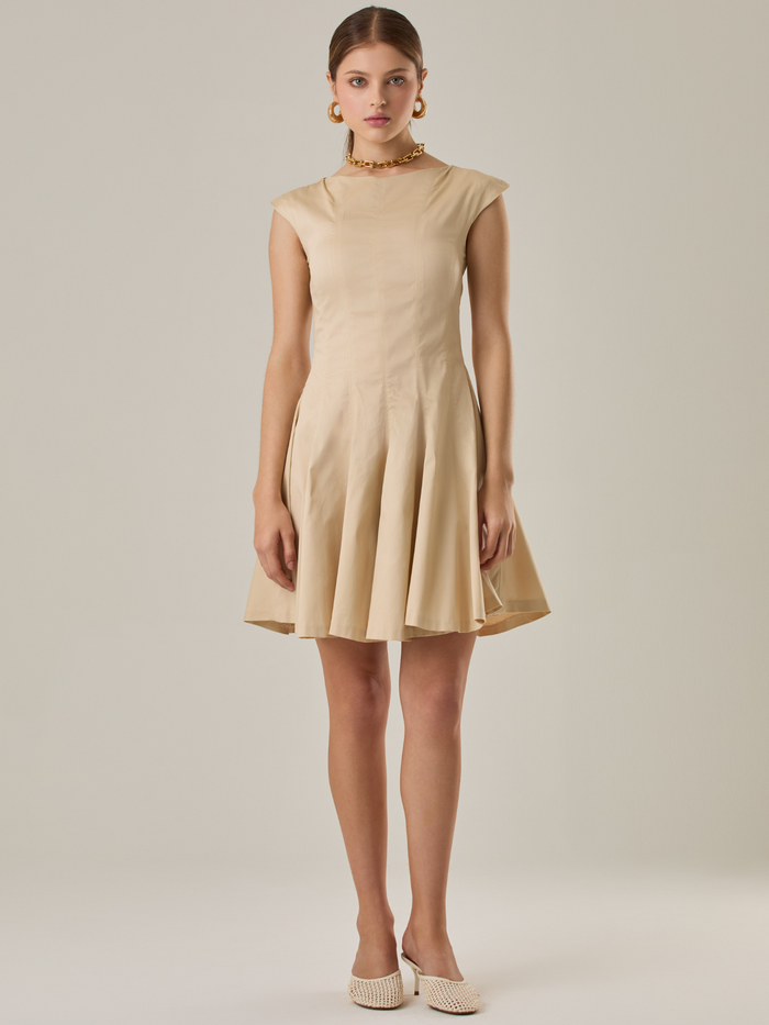 Vestido corto con silueta entallada en la parte superior y falda amplia. Tiene cuello cerrado tipo caja, mangas pequeñas que apenas cubren los hombros y costuras que definen la estructura del torso. La falda incorpora pliegues profundos que le dan volumen y movimiento. El largo llega por encima de la rodilla. Cierre invisible en la espalda.

Detalles:

Color: Ivory
