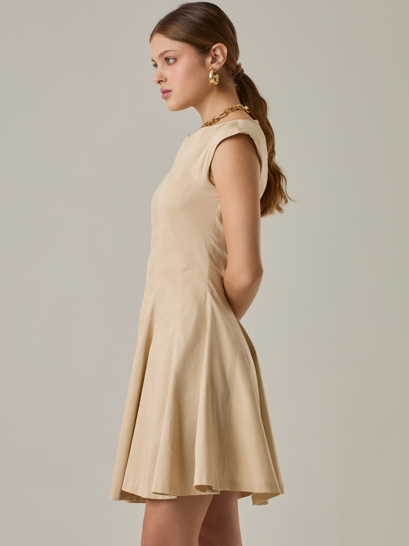 Vestido corto con silueta entallada en la parte superior y falda amplia. Tiene cuello cerrado tipo caja, mangas pequeñas que apenas cubren los hombros y costuras que definen la estructura del torso. La falda incorpora pliegues profundos que le dan volumen y movimiento. El largo llega por encima de la rodilla. Cierre invisible en la espalda.

Detalles:

Color: Ivory