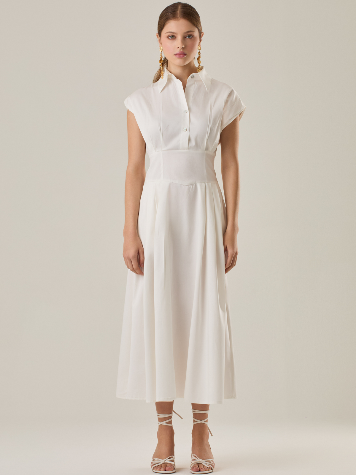 Vestido midi con inspiración safari, ideal para un look sofisticado y versátil. Su diseño con cuello camisero y botones aporta un aire elegante, mientras que los pliegues en la cintura estilizan la silueta. Perfecto para combinar con sandalias o tacones y lograr un outfit atemporal.