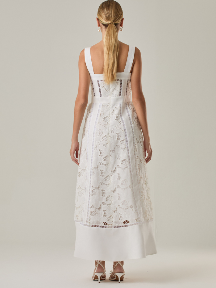 Vestido largo con tirantes anchos y escote recto, confeccionado en encaje floral con detalles calados que recorren el diseño de forma vertical. La base en contraste añade profundidad y estructura al diseño, mientras que el dobladillo liso aporta un toque de sobriedad que equilibra la delicadeza del encaje. Ideal para ocasiones especiales con un aire romántico y refinado.