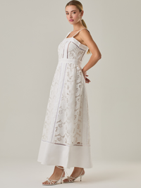 Vestido largo con tirantes anchos y escote recto, confeccionado en encaje floral con detalles calados que recorren el diseño de forma vertical. La base en contraste añade profundidad y estructura al diseño, mientras que el dobladillo liso aporta un toque de sobriedad que equilibra la delicadeza del encaje. Ideal para ocasiones especiales con un aire romántico y refinado.