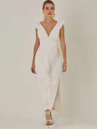 Este vestido tiene un aire delicado y femenino. Es de largo midi, con escote en “V” profundo al frente y en la espalda, y detalles de volantes en los tirantes. La parte trasera se ajusta con un lazo, dejando una abertura que resalta la cintura. El textil tiene un sutil bordado de hojas y flores, aportando textura sin ser recargado. El corte favorece la silueta y la abertura lateral en la falda añade movimiento al caminar. Ideal para eventos elegantes en climas cálidos.
