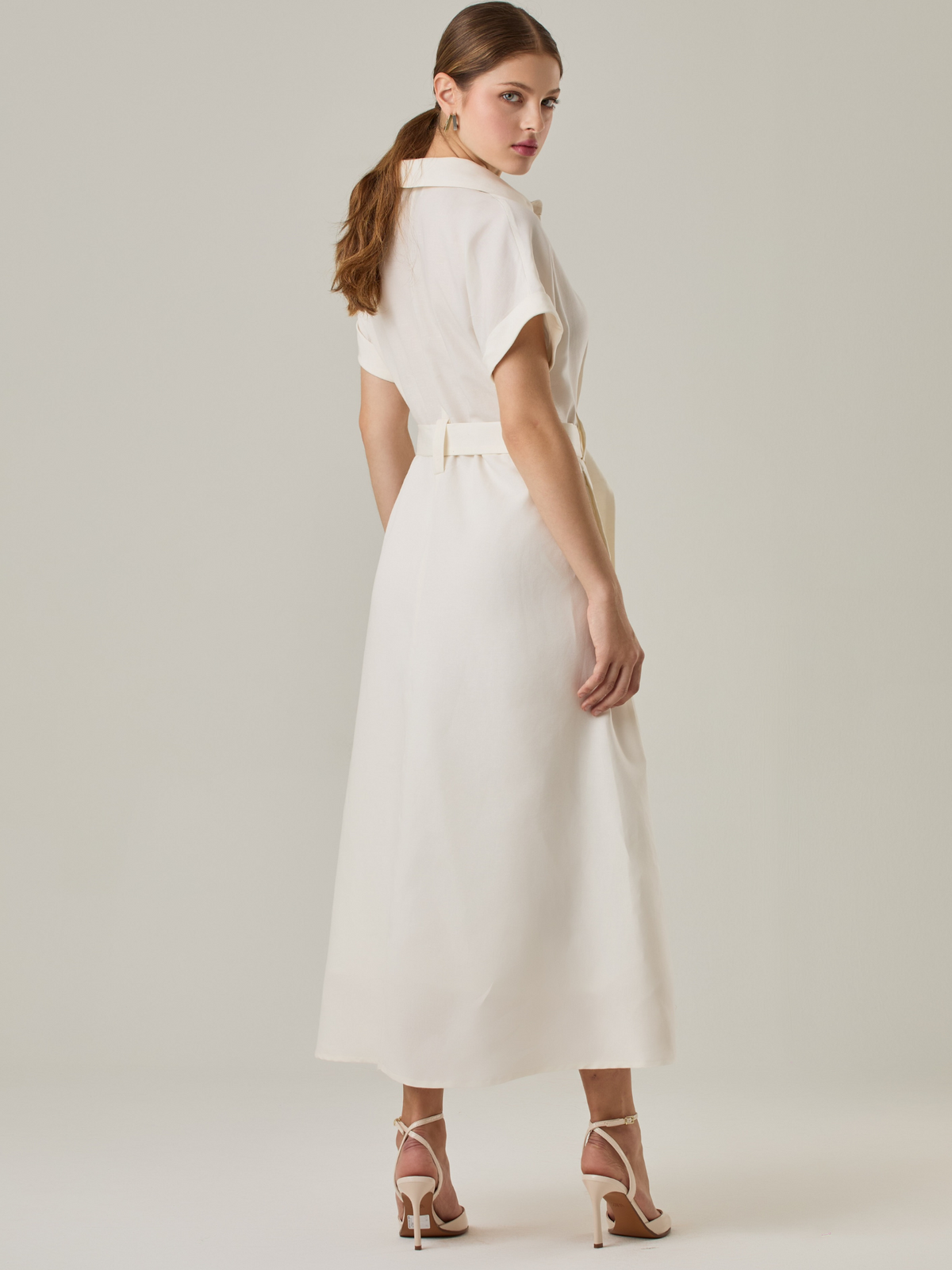 Vestido camisero de silueta midi con botonadura frontal completa y mangas cortas dobladas que aportan un aire relajado. Incorpora un cinturón del mismo material con hebilla forrada que define la cintura y realza la figura. Su estructura lo hace una prenda práctica y atemporal, perfecta para ocasiones casuales o más sofisticadas según cómo se combine. elegante 