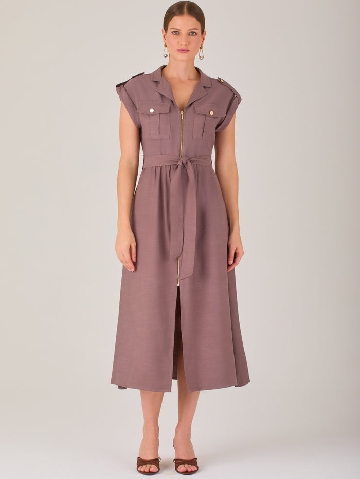 Diseño atemporal con carácter. Este vestido midi sin mangas combina estructura y feminidad con detalles utilitarios como bolsillos frontales, cierre metálico y solapas marcadas. El cinturón en la cintura permite ajustar la silueta, creando un look pulido ideal para la oficina, eventos casuales o estilismos urbanos con elegancia natural.