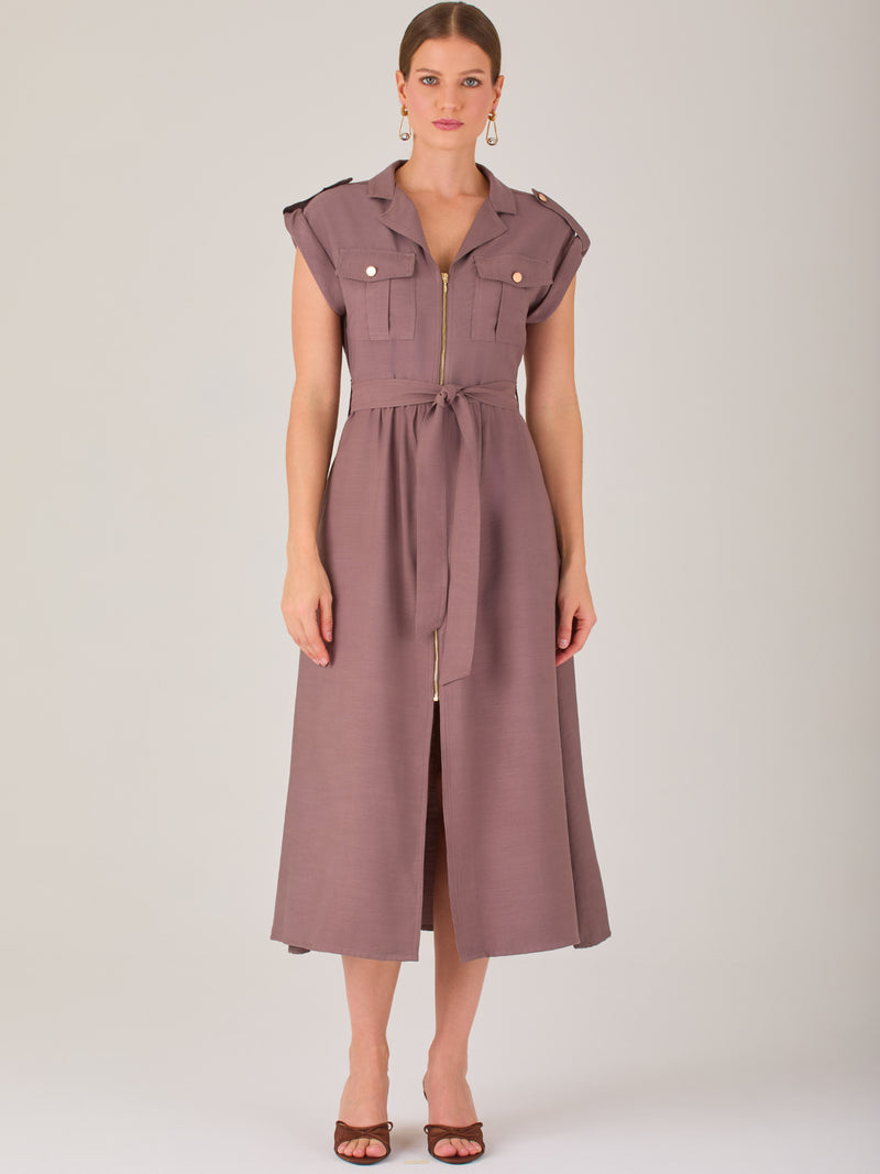 Diseño atemporal con carácter. Este vestido midi sin mangas combina estructura y feminidad con detalles utilitarios como bolsillos frontales, cierre metálico y solapas marcadas. El cinturón en la cintura permite ajustar la silueta, creando un look pulido ideal para la oficina, eventos casuales o estilismos urbanos con elegancia natural.