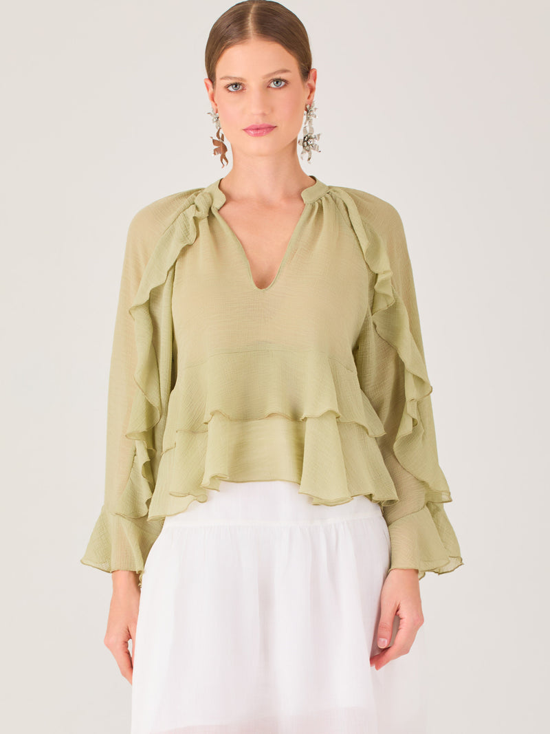 Ligera y romántica, esta blusa de textura vaporosa destaca por sus volantes en capas que aportan movimiento y fluidez. El escote en V y las mangas amplias con acabado ondulado añaden un toque delicado y sofisticado. Ideal para ocasiones especiales, cenas o estilismos casuales con un aire femenino y refinado.