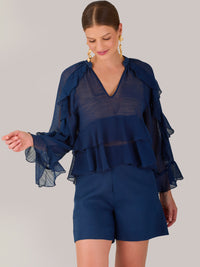 Ligera y romántica, esta blusa de textura vaporosa destaca por sus volantes en capas que aportan movimiento y fluidez. El escote en V y las mangas amplias con acabado ondulado añaden un toque delicado y sofisticado. Ideal para ocasiones especiales, cenas o estilismos casuales con un aire femenino y refinado.