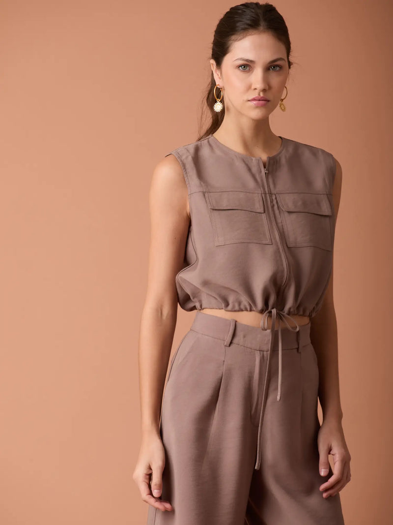 Blusa Ardaza Café corta con bolsillos superiores y cordón ajustable para un estilo casual sofisticado.