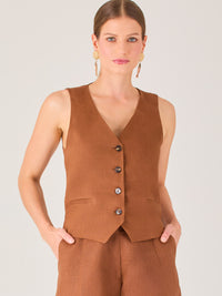 Esta blusa tipo chaleco es ideal para climas cálidos o para crear looks sofisticados con un aire casual. Presenta un corte recto ligeramente entallado que acentúa la silueta de forma sutil, y un escote en “V” que estiliza el cuello. Cuenta con una botonadura frontal compuesta por cinco botones oscuros que contrastan elegantemente con el tono neutro de la prenda. También incorpora bolsillos falsos decorativos a ambos lados del frente, que añaden un detalle sutil al diseño minimalista. Esta pieza es versátil 