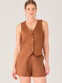 Esta blusa tipo chaleco es ideal para climas cálidos o para crear looks sofisticados con un aire casual. Presenta un corte recto ligeramente entallado que acentúa la silueta de forma sutil, y un escote en “V” que estiliza el cuello. Cuenta con una botonadura frontal compuesta por cinco botones oscuros que contrastan elegantemente con el tono neutro de la prenda. También incorpora bolsillos falsos decorativos a ambos lados del frente, que añaden un detalle sutil al diseño minimalista. Esta pieza es versátil 