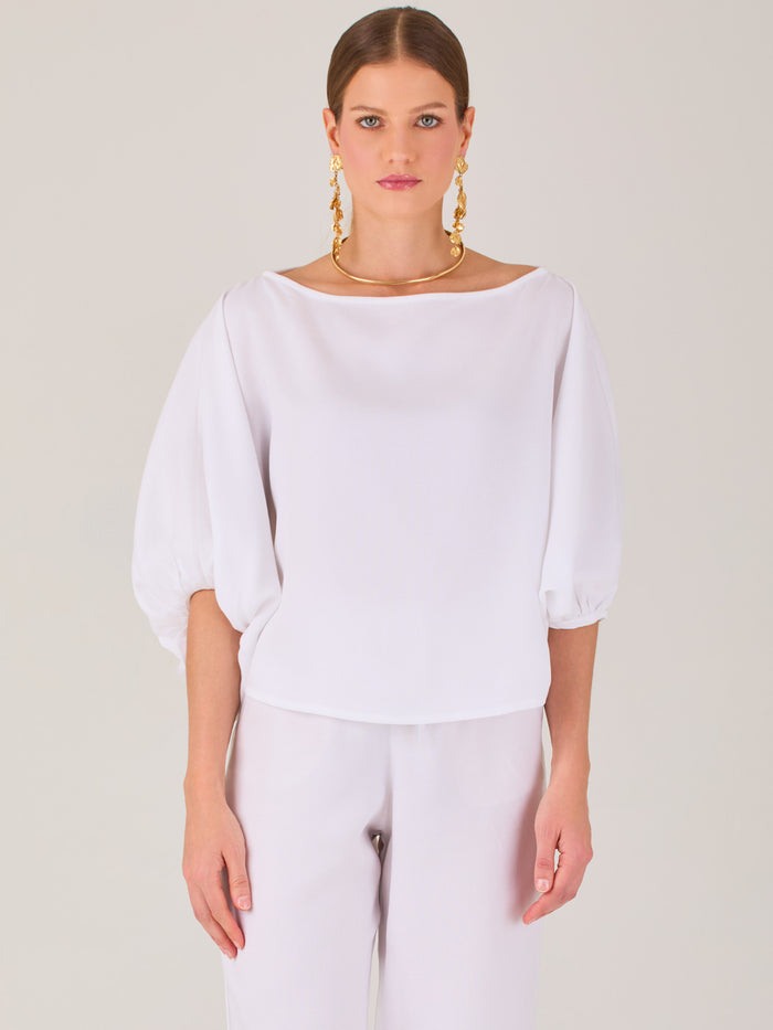 Sofisticada y atemporal, esta blusa de silueta recta se caracteriza por su escote cerrado, líneas limpias y mangas tres cuartos con efecto globo. El diseño pulido la convierte en una prenda versátil para combinar con prendas sastre o looks relajados, ideal para ambientes laborales o estilismos casuales con elegancia natural.