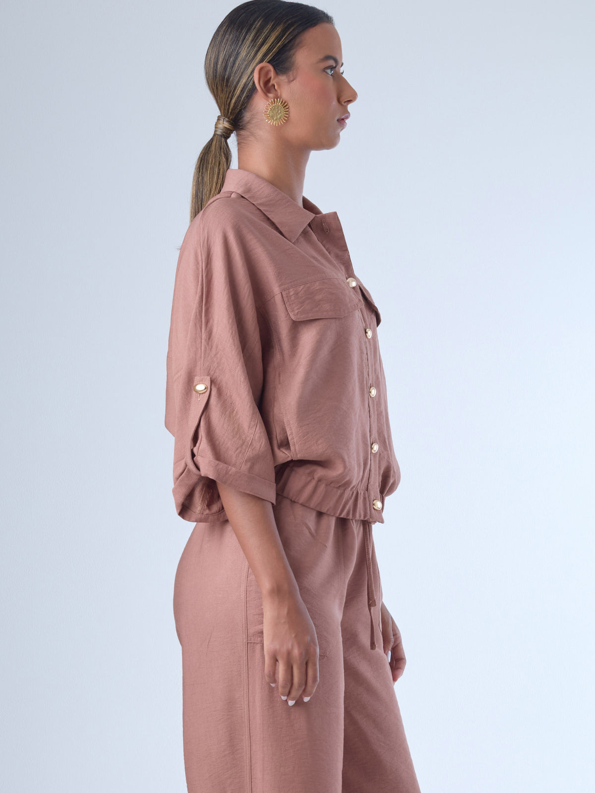 Relajada pero estructurada, esta blusa de silueta amplia combina un diseño utilitario con detalles refinados. Presenta bolsillos de solapa en el pecho, mangas con opción de ajuste y una botonadura dorada que aporta un toque de brillo sutil. Ideal para estilismos casuales con elegancia natural, o para elevar conjuntos relajados con una prenda clave y atemporal.