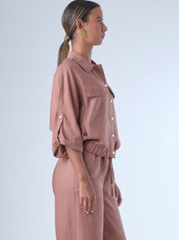 Relajada pero estructurada, esta blusa de silueta amplia combina un diseño utilitario con detalles refinados. Presenta bolsillos de solapa en el pecho, mangas con opción de ajuste y una botonadura dorada que aporta un toque de brillo sutil. Ideal para estilismos casuales con elegancia natural, o para elevar conjuntos relajados con una prenda clave y atemporal.