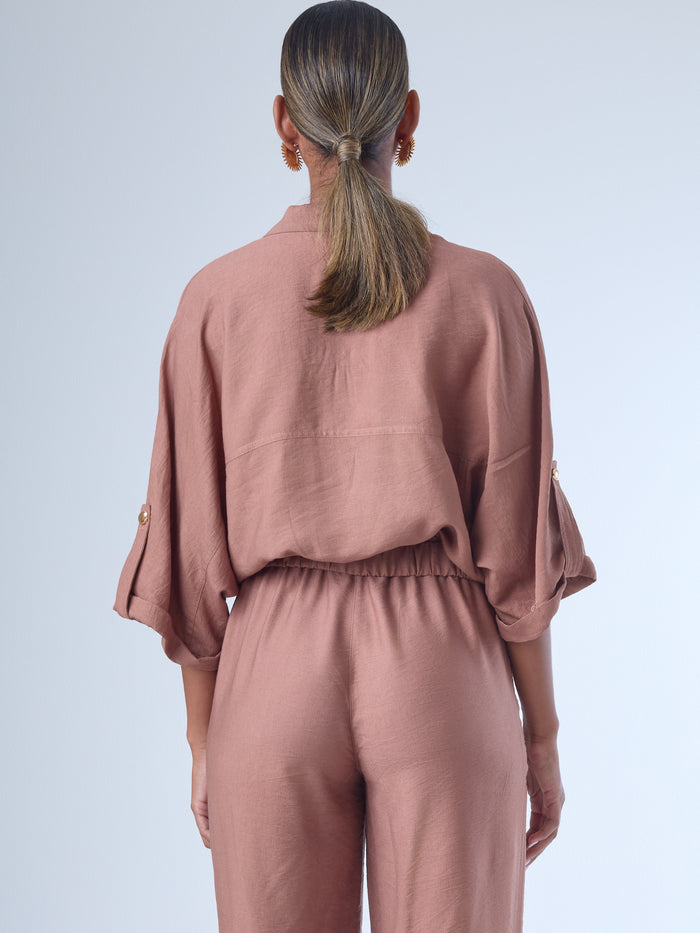 Relajada pero estructurada, esta blusa de silueta amplia combina un diseño utilitario con detalles refinados. Presenta bolsillos de solapa en el pecho, mangas con opción de ajuste y una botonadura dorada que aporta un toque de brillo sutil. Ideal para estilismos casuales con elegancia natural, o para elevar conjuntos relajados con una prenda clave y atemporal.