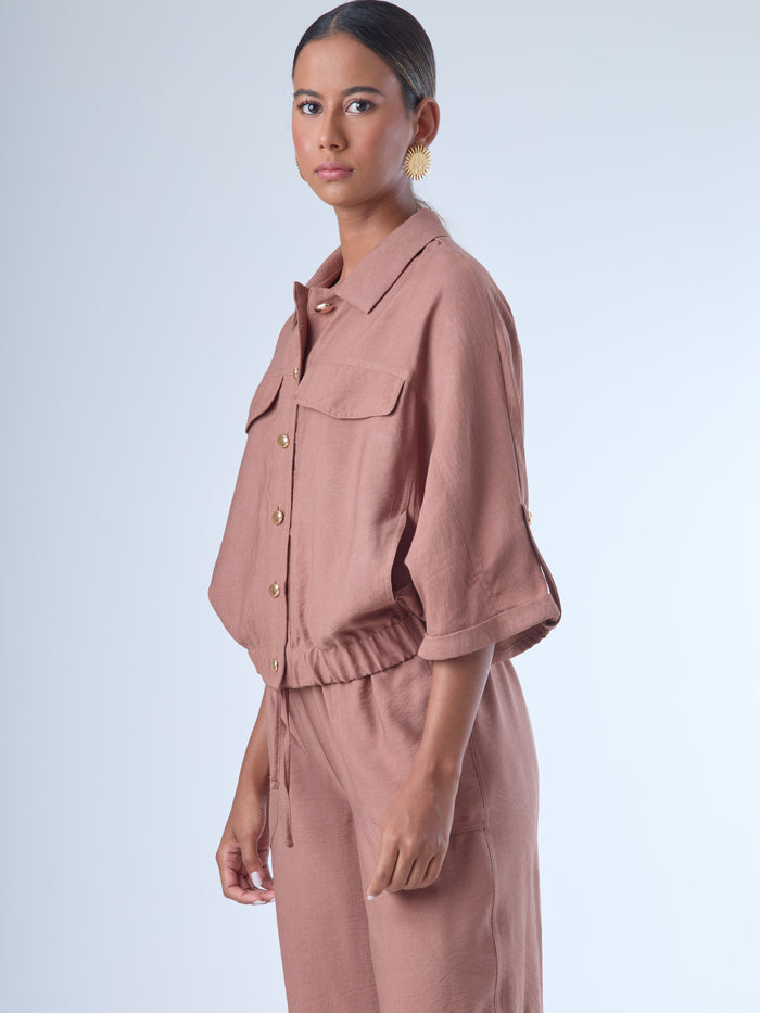 Relajada pero estructurada, esta blusa de silueta amplia combina un diseño utilitario con detalles refinados. Presenta bolsillos de solapa en el pecho, mangas con opción de ajuste y una botonadura dorada que aporta un toque de brillo sutil. Ideal para estilismos casuales con elegancia natural, o para elevar conjuntos relajados con una prenda clave y atemporal.