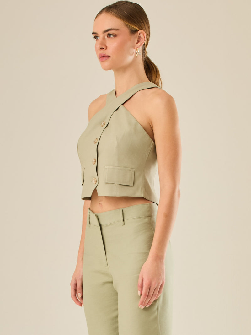 Chaleco corto con escote halter cruzado y cierre frontal con botones, ideal para un look moderno y sofisticado. Su diseño estructurado realza la figura con elegancia, perfecto para combinar con prendas de tiro alto y crear conjuntos contemporáneos con personalidad.

Detalles:

Color: Verde