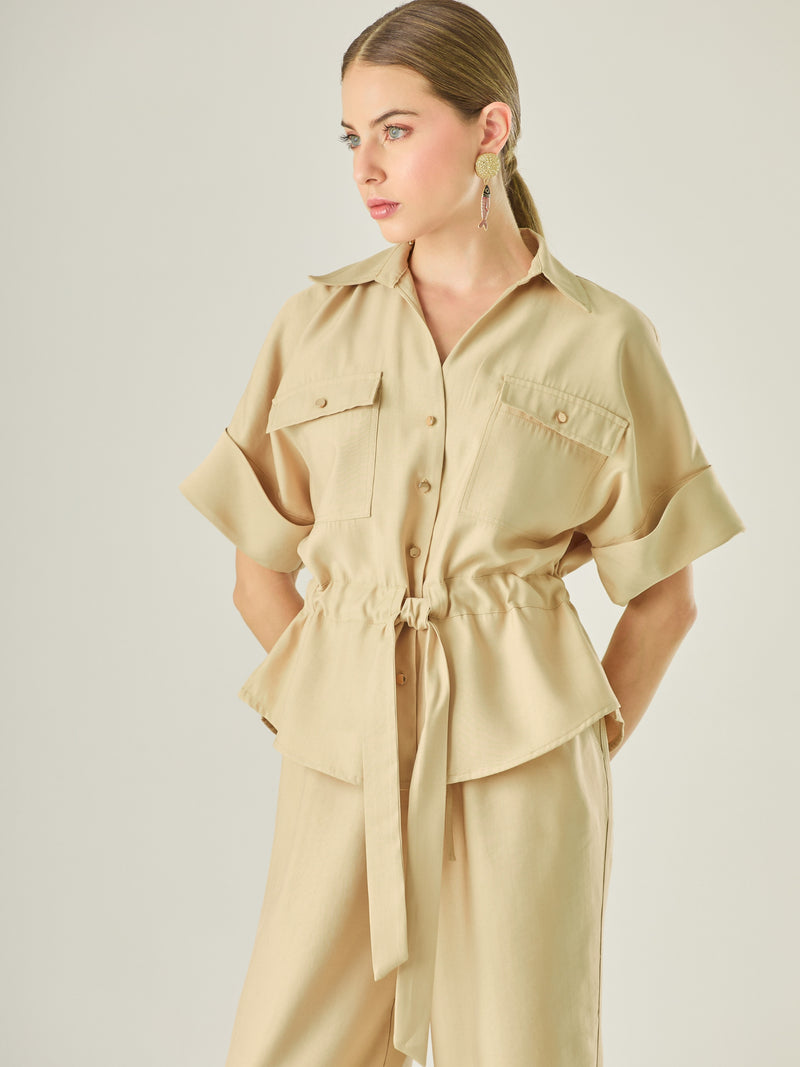 Blusa tipo camisera con manga corta amplia, bolsillos frontales y ajuste en la cintura con lazo para definir la silueta. Su diseño estructurado y moderno combina funcionalidad y estilo, ideal para lograr un look casual con un aire sofisticado.

Detalles:

Color: Camel