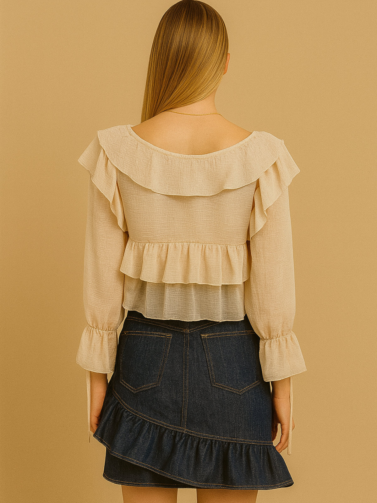 Fresca y femenina, esta blusa corta destaca por sus delicados volantes en el escote y el cuerpo, creando movimiento y suavidad visual. Con mangas largas de puño fruncido y amarre en el escote, es una prenda ideal para looks bohemios y estilismos relajados con un toque romántico. Perfecta para combinar con prendas de tiro alto en ocasiones casuales con estilo.