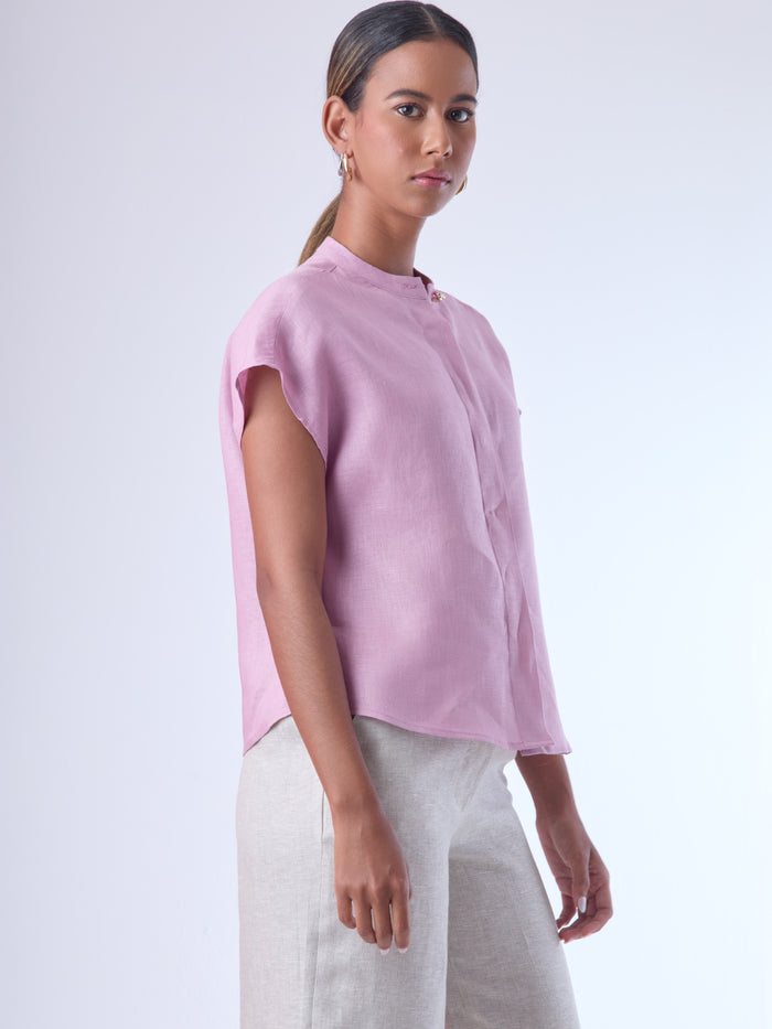 Blusa de silueta recta con manga corta tipo caída y estructura relajada. Cuenta con cuello que se cierra con un pequeño broche metálico decorativos estilo sobrio la hace versátil y elegante, ideal para atuendos casuales o más refinados.